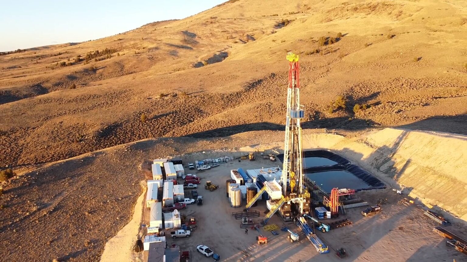 Natural gas drilling operation in Wyoming showing drilling rig and support equipment in desert landscape